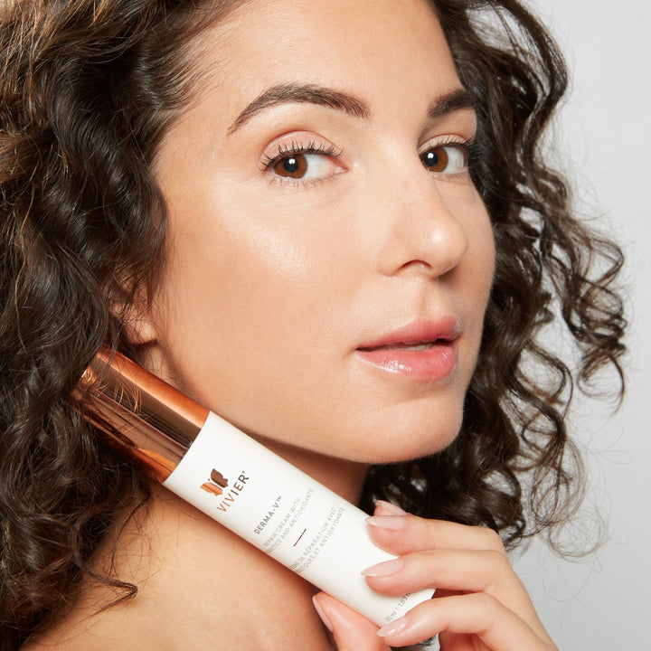 Model holding Vivier DERMA-V cream near her face, showcasing smooth, hydrated, glowing skin.
